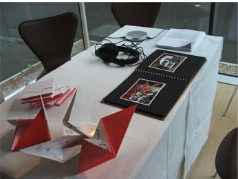 table, with white cloth, chair with CD covers, earphones and photo album